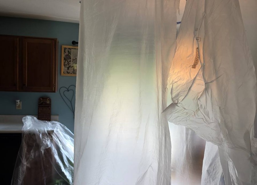 Dust confinement setup in a Louisville home with ZipWall plastic barriers and floor protection before drywall ceiling work